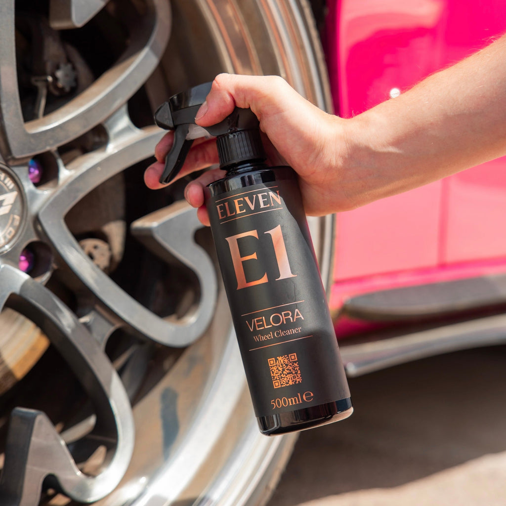 Person holding a bottle of E1 Velora product near a car wheel