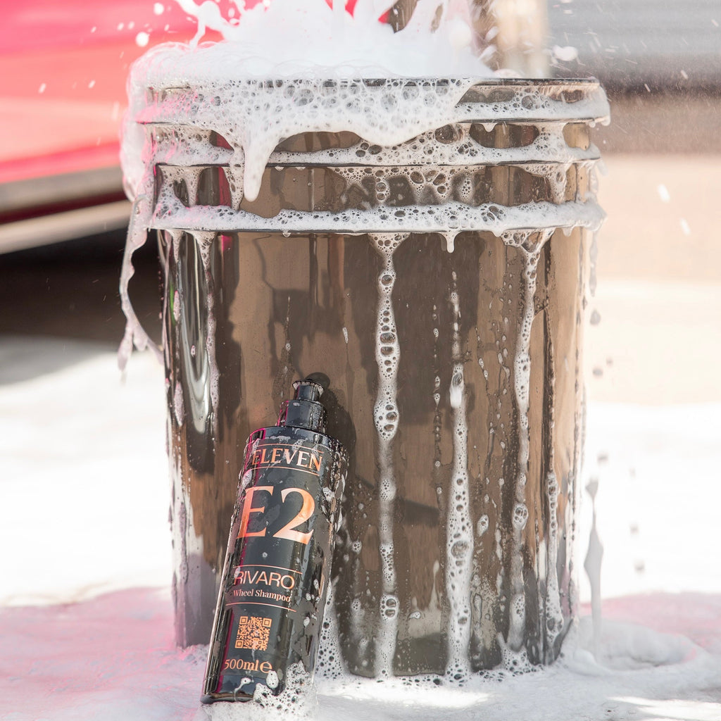 Car wash with a bottle of E2 Rivaro wheel shampoo being used on a car.
