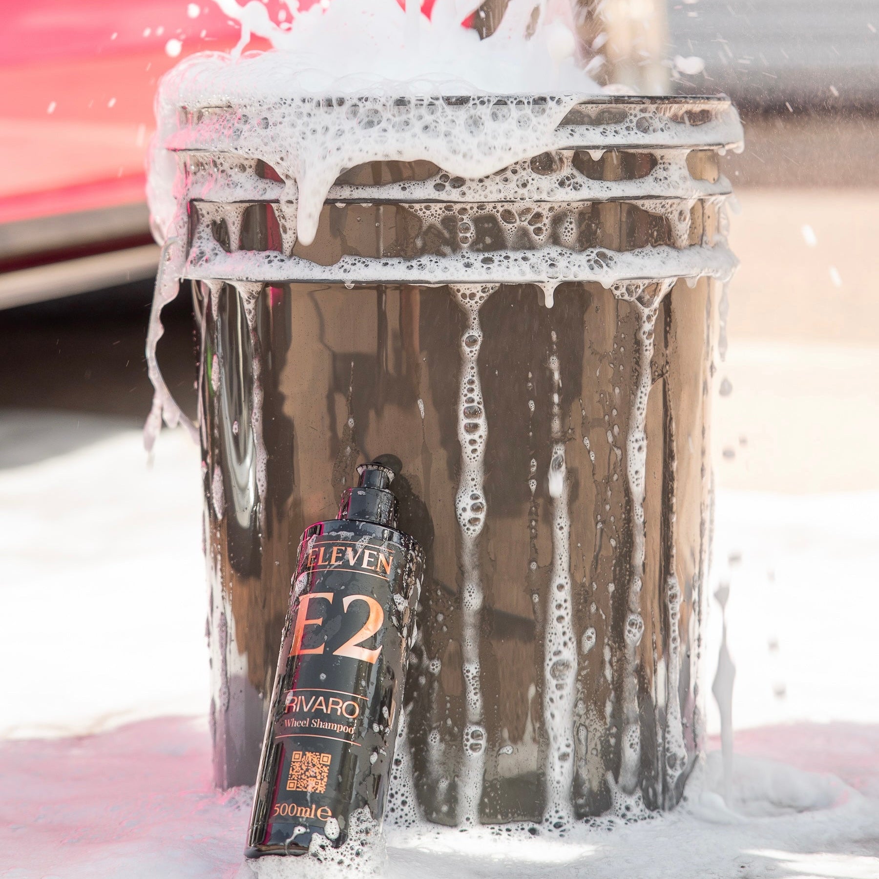 Car wash with a bottle of E2 Rivaro wheel shampoo being used on a car.