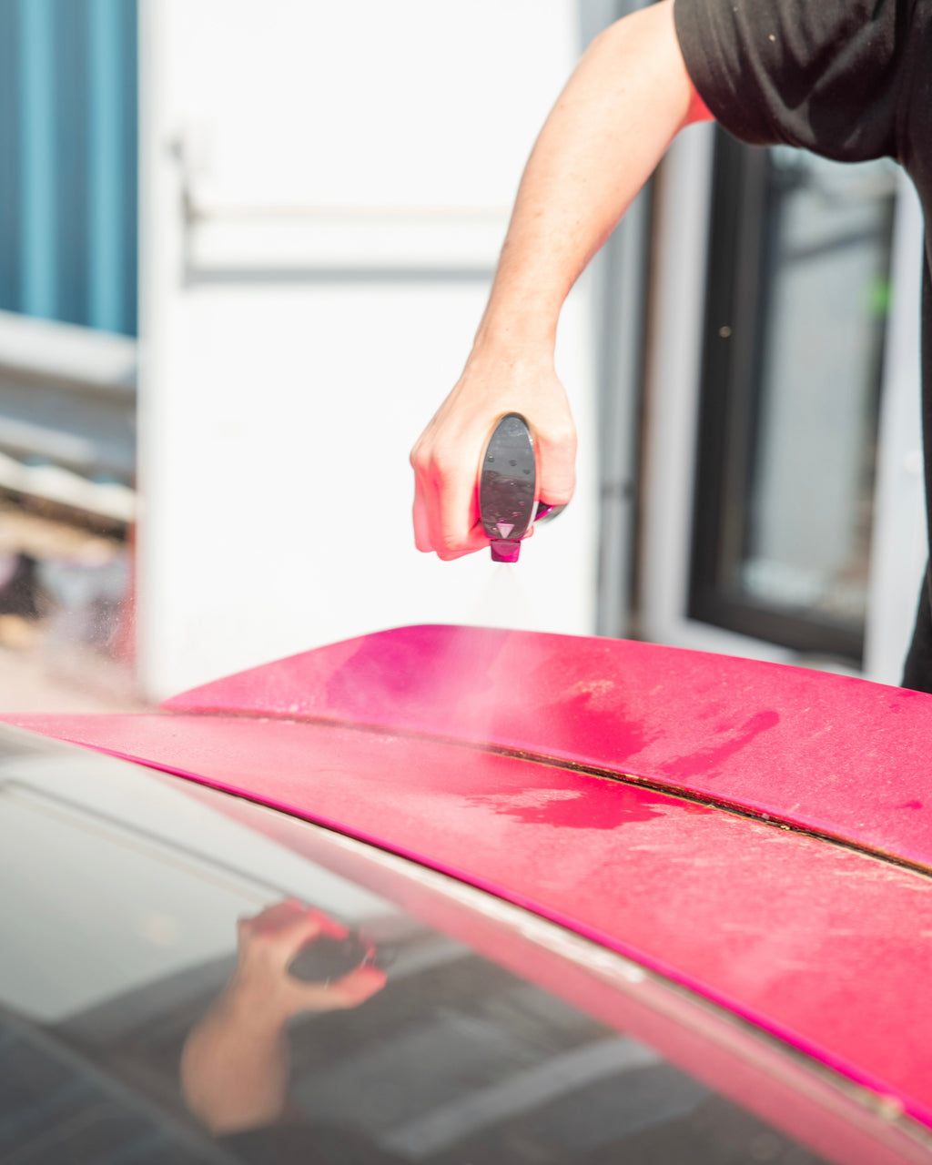 Person applying citrus pre wash on a pink car wrap.