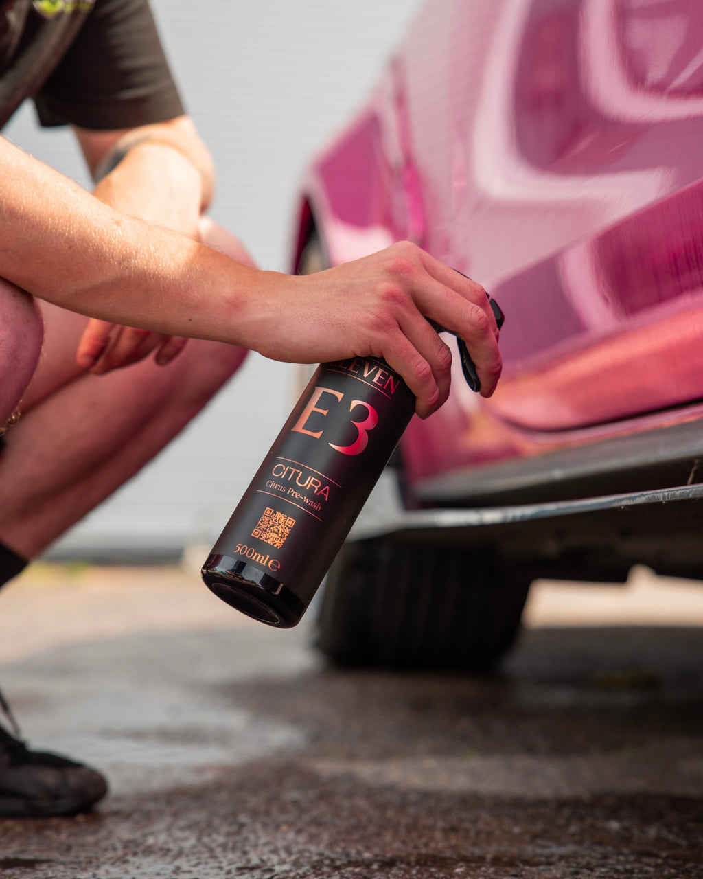 Person using a bottle labeled 'E3' on a car