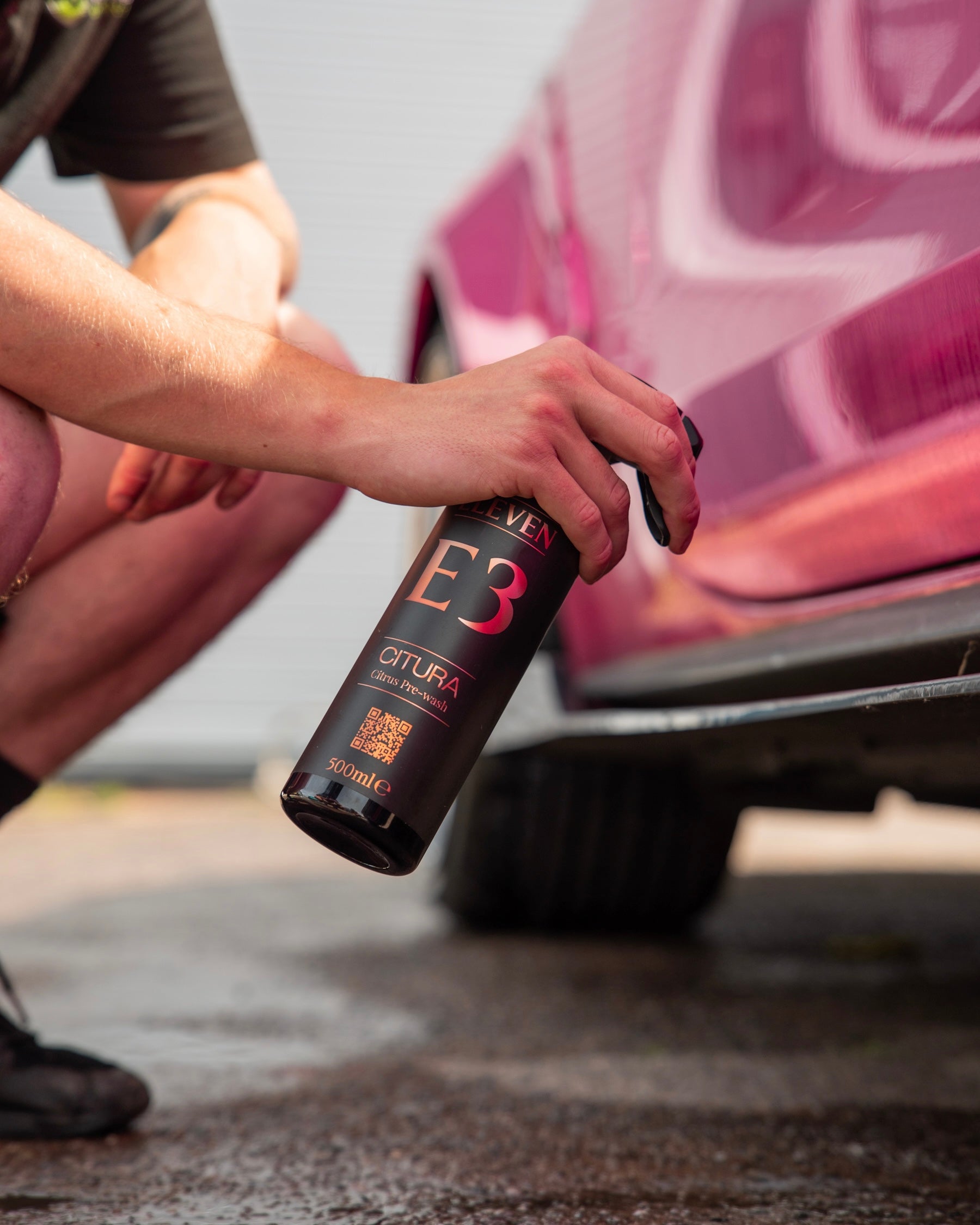 Person using a bottle labeled 'E3' on a car