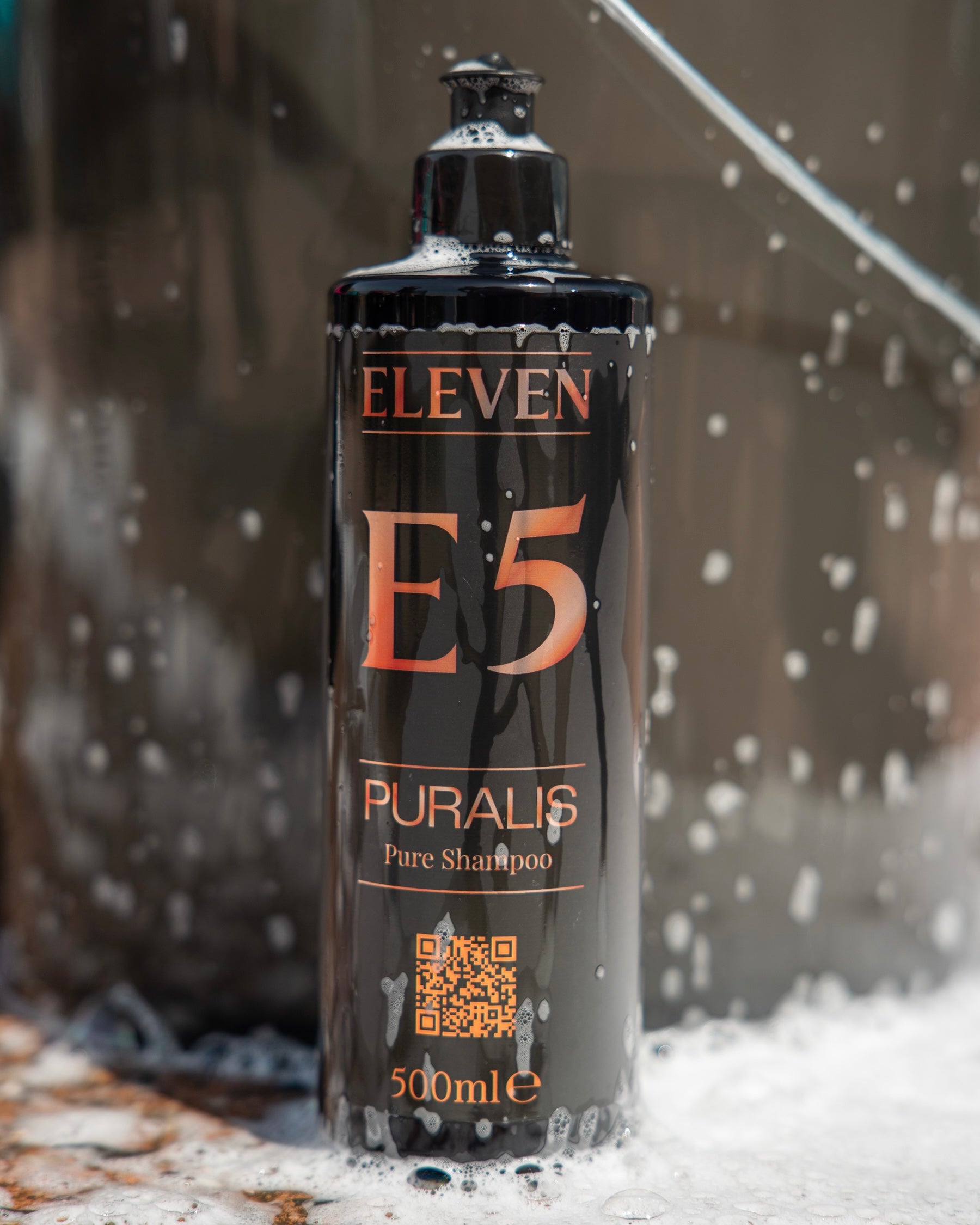 Shampoo bottle labeled 'E11 E5 Puralis' with water droplets on a blurred background