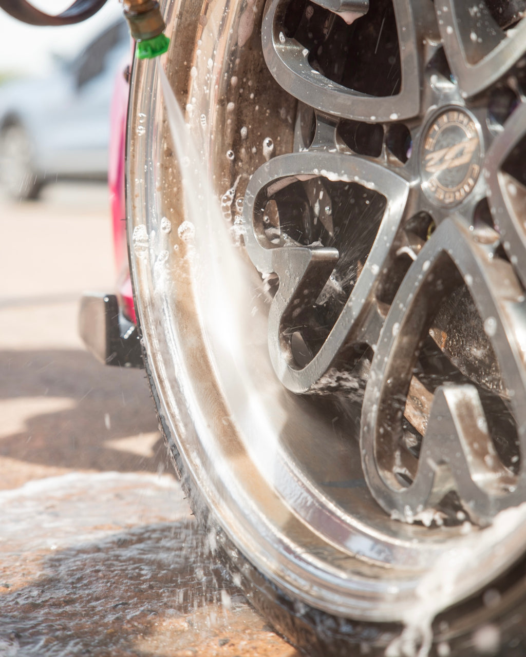 Close-up of a car wheel being rinsed with a water from a shampoo foam