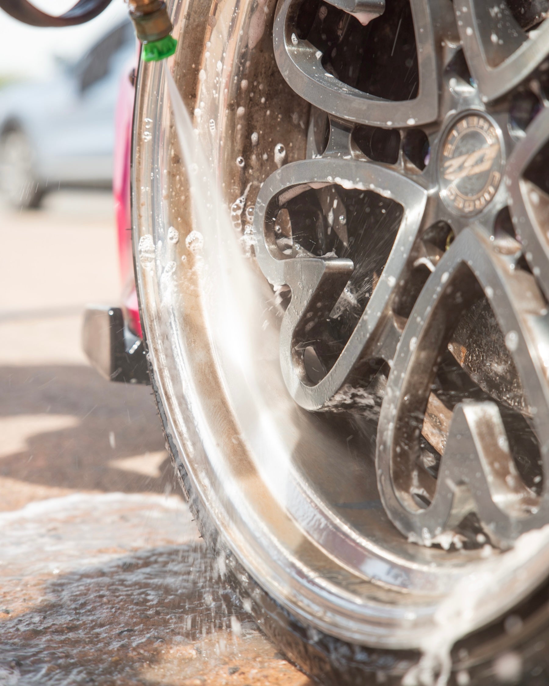 Close-up of a car wheel being rinsed with a water from a shampoo foam