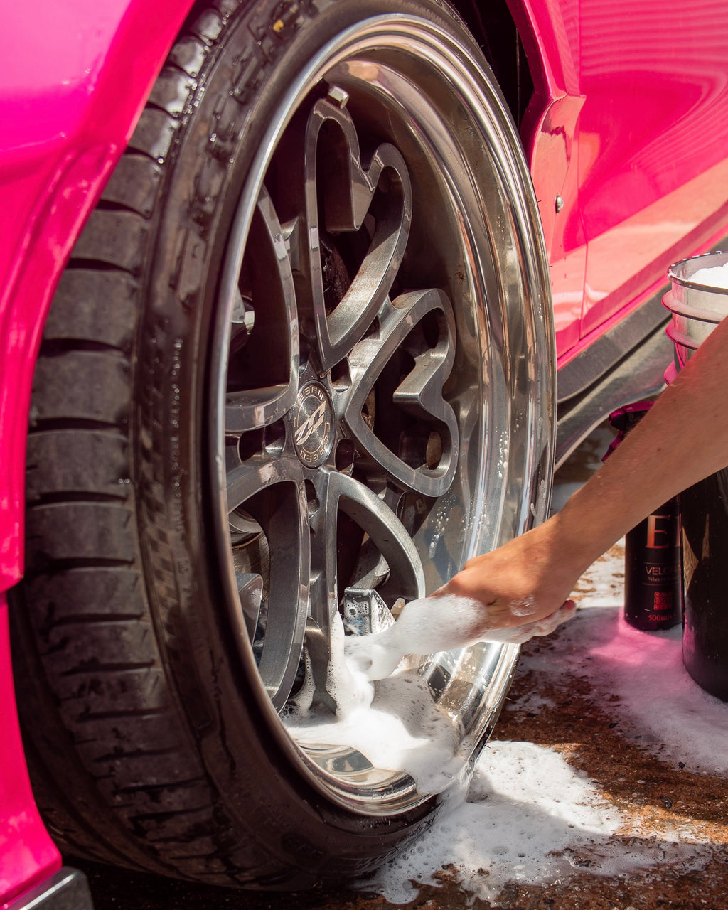 Person cleaning a wheel with foam water